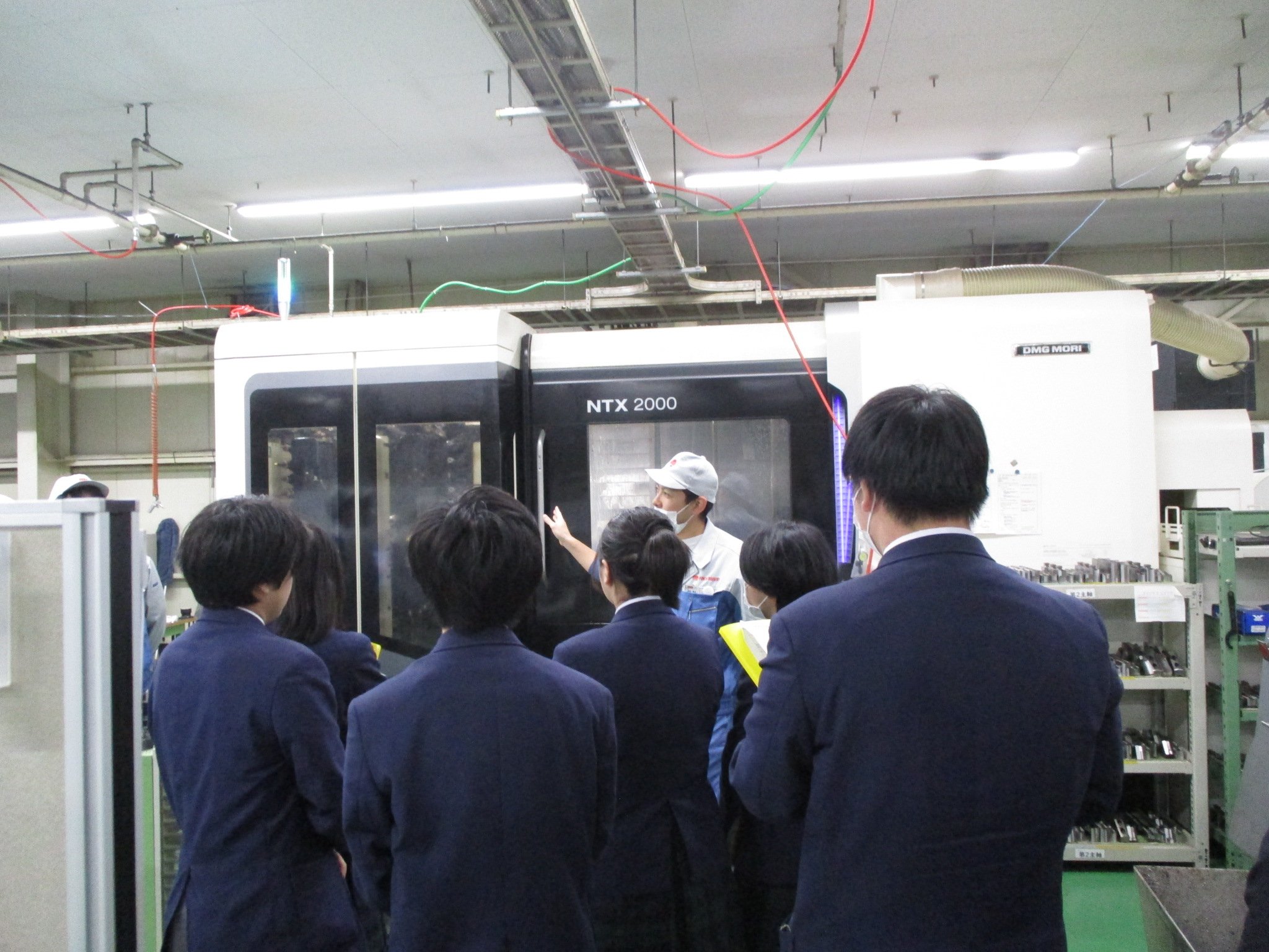 加工機の説明を受ける高校生の後ろ姿